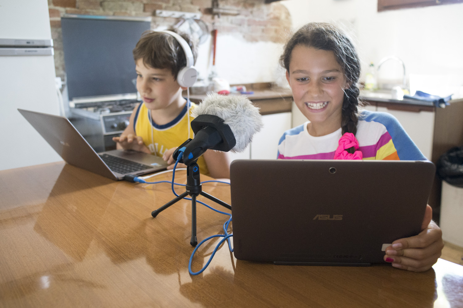Due bambini registrano o preparano una traccia audio davanti a un microfono e a due computer