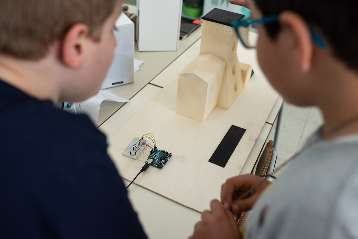 Studenti osservano il circuito elettronico accanto a un modello Hi-Storia